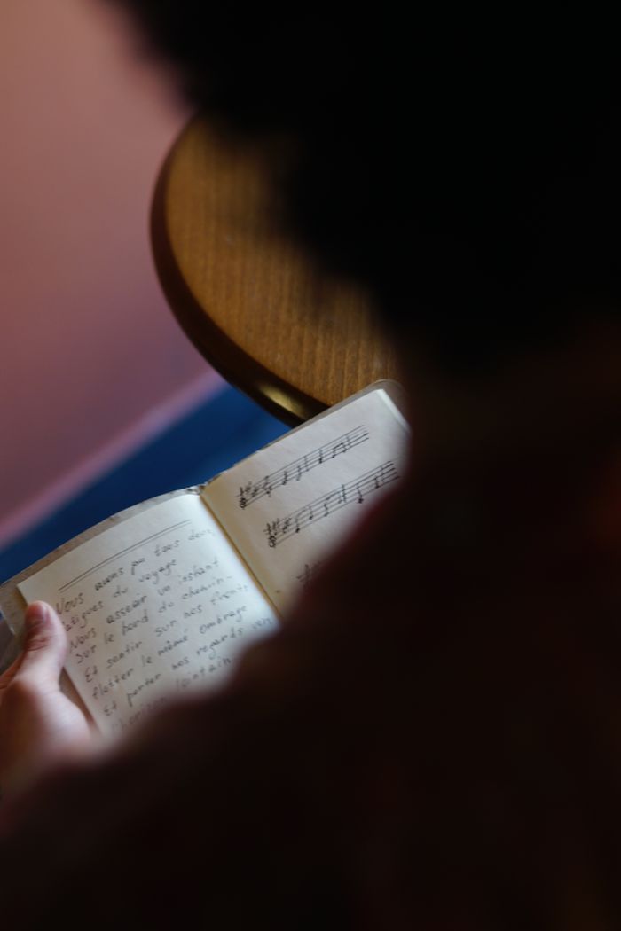 A person reads a notebook with handwritten music notes. Captured in a cozy setting.